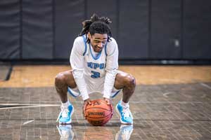 Basketball player crouched holding ball.